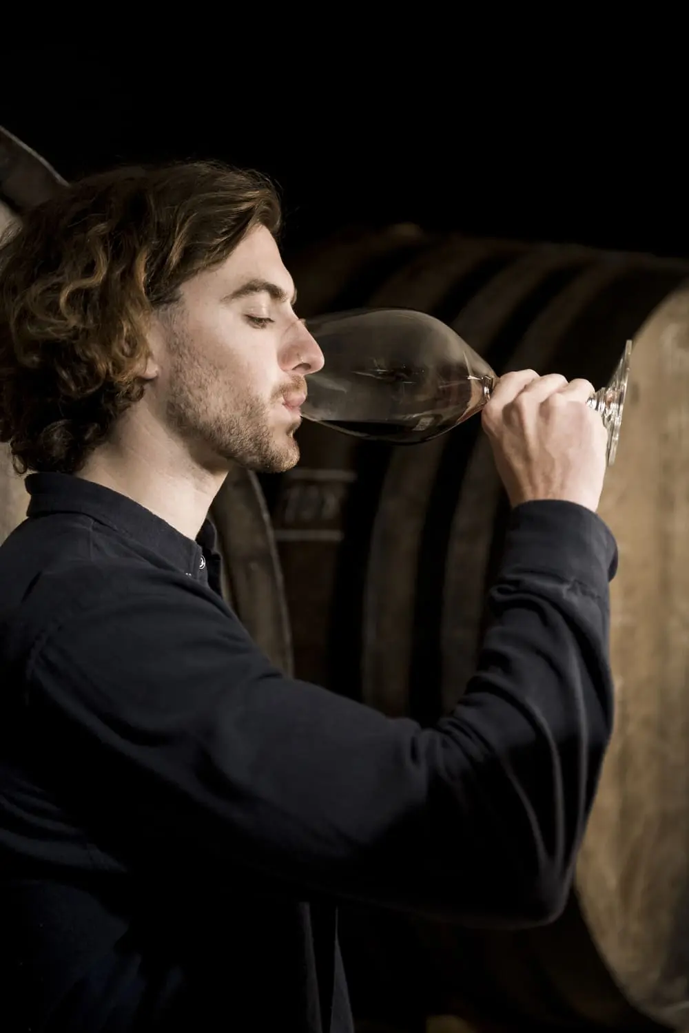 Man drinking wine in barrel room